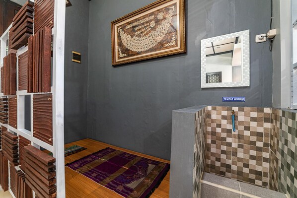 Una habitación con pared de baldosas a cuadros, una obra de arte enmarco, un espejo y una estantería de madera.