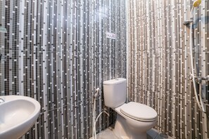A bathroom with a mosaic tile wall, a toilet, and a sink. - RedDoorz Syariah near RRI Malang (Malang)