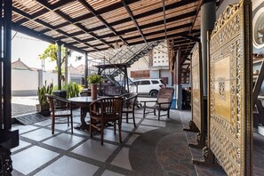 An outdoor patio area with a wooden table and chairs, a potted plant, and a decorative wall panel. - RedDoorz Syariah near RRI Malang (Malang)