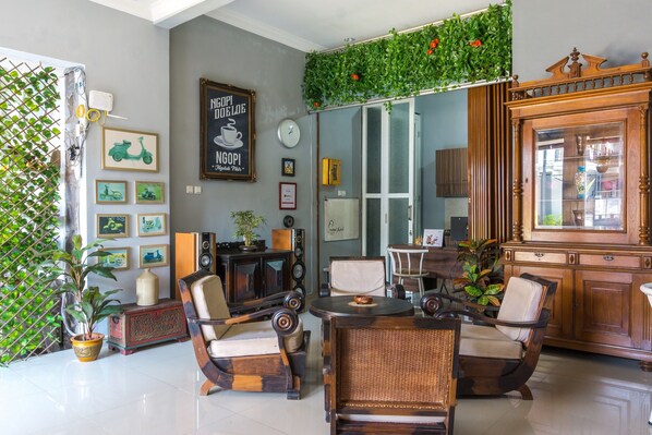 A modern living room with a sofa set, a dining table, and a wooden cabinet. - RedDoorz Syariah near RRI Malang (Malang)