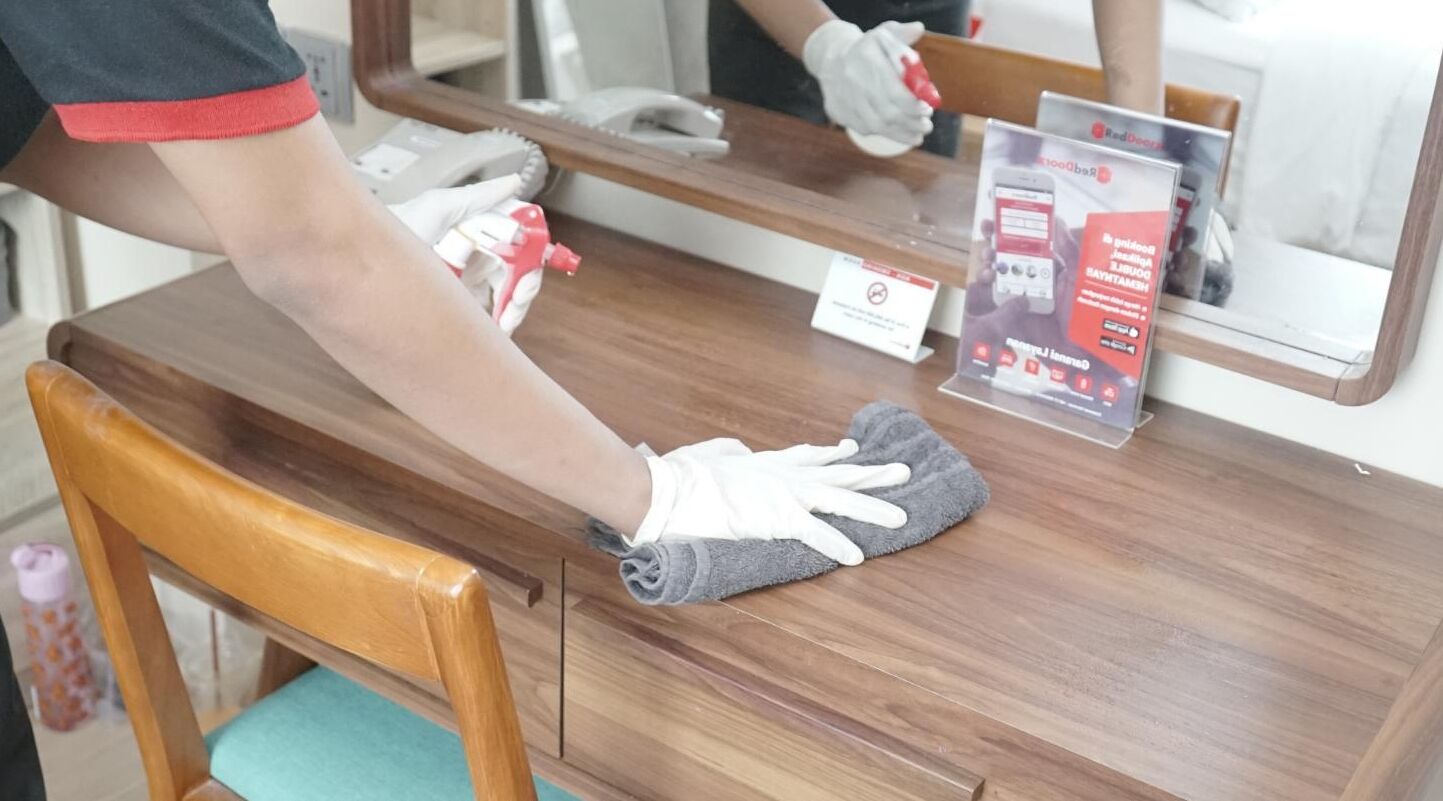 A person cleaning a wooden counter with a cloth.