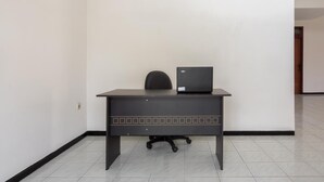 A desk with a laptop in a room with white walls and tiled flooring. - RedDoorz near Universitas Widyagama Malang (Malang)