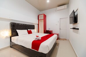 A modern hotel room with a large bed, a red accent wall, a flat-screen TV mounted on the wall, and a small desk with a chair. - RedDoorz Plus near Palembang Icon Mall 2 (Palembang)