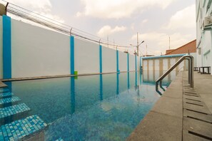 A swimming pool with clear water, blue steps, and a metal handrail. - RedDoorz Plus near Palembang Icon Mall 2 (Palembang)
