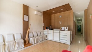 Eine moderne Hotellobby mit Empfangstresen, Sitzgelegenheiten und einer Wand mit Holzapplikationen.