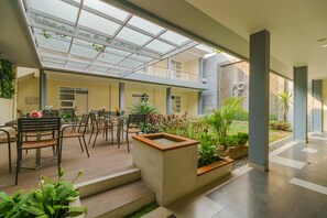 Un vaste patio intérieur doté d’un toit en verre, d’un plancher en bois et de plusieurs espaces aménagés pour s’asseoir.