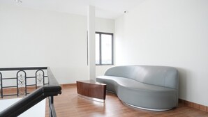Un salon moderne avec un canapé gris, une table basse en bois et un escalier doté d’une rampe en métal.