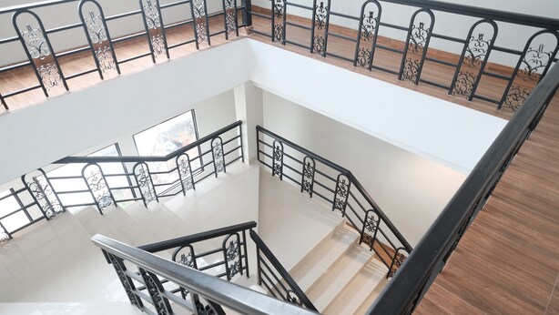 Un intérieur à plusieurs niveaux, doté d’un escalier central, de rampes en métal et d’un plancher en bois.