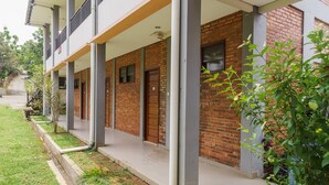 A building with a brick facade, a covered walkway, and a grassy area with plants.