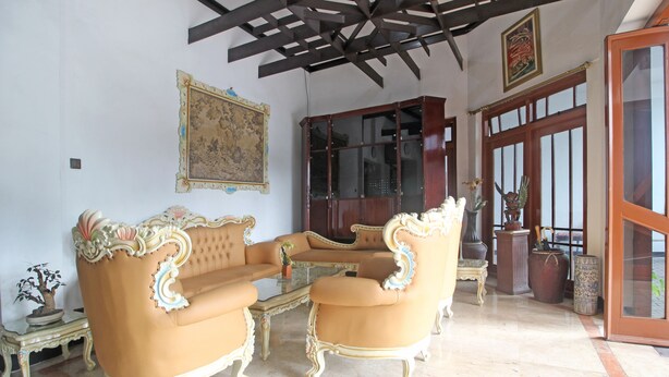 A room with a traditional sofa set, a cabinet, and a large window. - RedDoorz Plus @ Taman Siswa 3 (Yogyakarta)