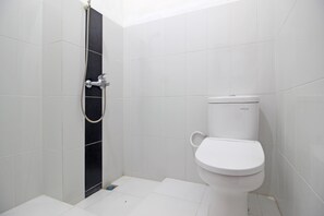 Een badkamer met witte tegels, een zwarte douchewand, een wit toilet en een douchekop.