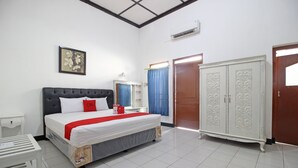A neatly arranged hotel room with a large bed, a wardrobe, a bedside table, and a mirror. - RedDoorz Plus @ Taman Siswa 3 (Yogyakarta)