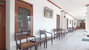 A hallway with wooden benches and a tiled floor, leading to a door at the end. - RedDoorz Plus @ Taman Siswa 3 (Yogyakarta)