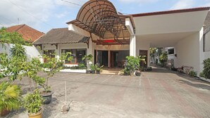 A building with a covered entrance, potted plants, and a tiled roof. - RedDoorz Plus @ Taman Siswa 3 (Yogyakarta)