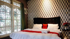 A neatly made bed with white bedding and red accents, a dark headboard, and a patterned wall behind it. - Residences by RedDoorz near Taman Safari (Cisarua)