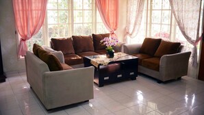 A living room with a sofa set, a coffee table, and curtains. - Residences by RedDoorz near Taman Safari (Cisarua)