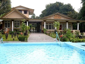 Un edificio con la leyenda "KAVIO RESORT" y un área de piscina al frente.