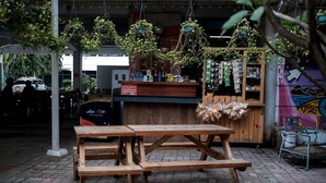 A wooden picnic table with benches, hanging plants, and a counter with various items. - RedDoorz @ Cempaka Putih Jambi (Jambi)