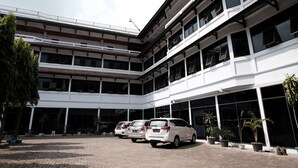 A multi-story building with a parking area in front. - RedDoorz @ Cempaka Putih Jambi (Jambi)