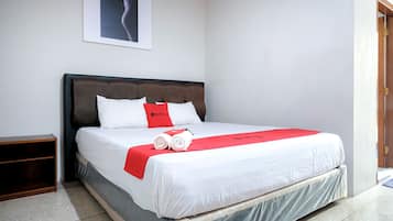 A neatly made bed with white bedding and a red accent pillow, a wooden nightstand, and a framed picture on the wall.