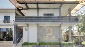A hotel entrance with a covered walkway, a signboard, and a staircase leading to the entrance.