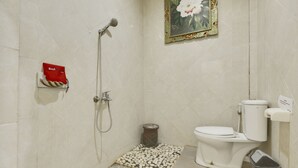 A bathroom with a toilet, bidet, shower, and a small decorative area with a picture frame.