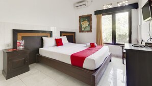 A hotel room with a large bed, a desk, a chair, a TV, and a window with curtains.