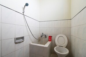 A small bathroom with a toilet, a shower, and a soap dish.