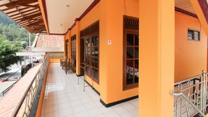 A covered balcony with a tiled floor, wooden railings, and a view of the surrounding area. - RedDoorz near Sarangan Lake (Plaosan)