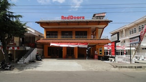 A two-story building with a red and white awning, a sign reading "RedDoorz", and a staircase on the left. - RedDoorz near Sarangan Lake (Plaosan)