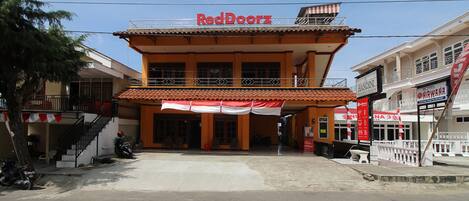 A two-story building with a red and white awning, a sign reading "RedDoorz", and a staircase on the left.