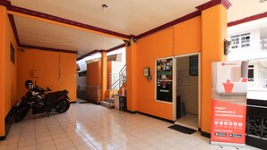 A hotel lobby with a motorcycle parked, a staircase, and a RedDoorz advertisement. - RedDoorz near Sarangan Lake (Plaosan)