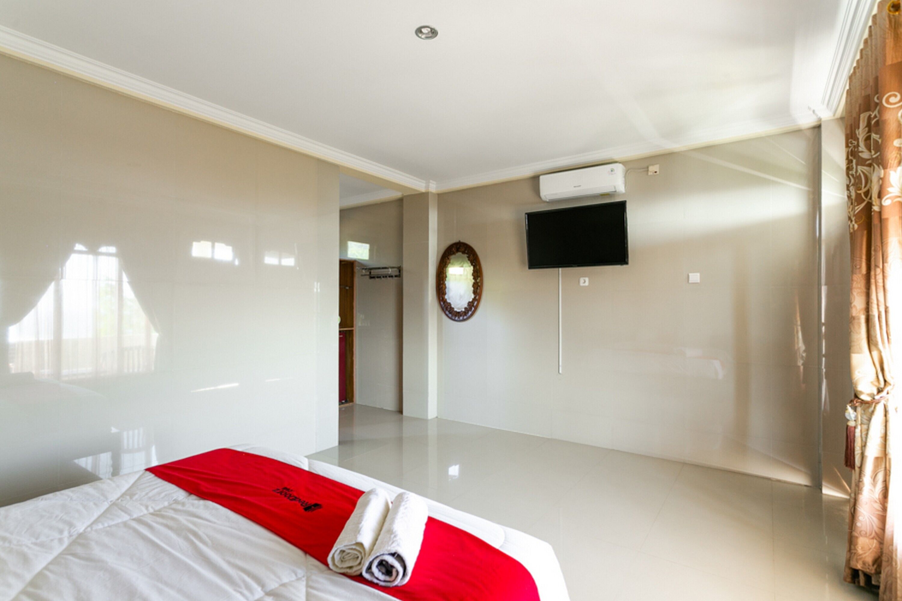 A hotel room with a bed, a flat-screen TV mounted on the wall, and a mirror.