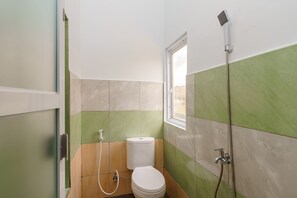 Ein kleines Badezimmer mit Toilette, Dusche und Fenster.