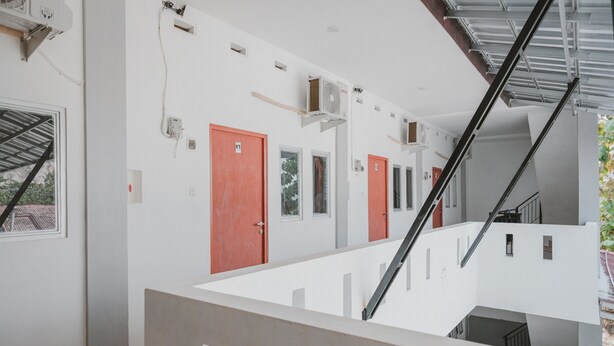 Een modern interieur met een trap, witte muren en rode deuren.