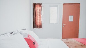 Een slaapkamer met een bed, een deur en een raam met gordijnen.