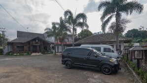 A black SUV parked on a dirt road in a residential area with houses and palm trees. - RedDoorz near Happy Farm Ciwidey (Rancabali)