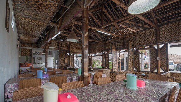 A restaurant with wooden beams and patterned walls, tables with patterned tablecloths, and chairs. - RedDoorz near Happy Farm Ciwidey (Rancabali)
