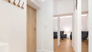 A hallway with a wooden door, a coat rack, and a seating area with chairs and a table. - Jerozolimskie Central View Apartment (Warsaw)