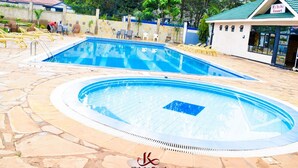 Una piscina con deck de azulejos, sillas de descanso y un edificio que dice 'K'aba Resort'.