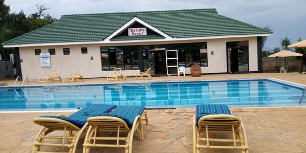 Un espace piscine avec des chaises longues et un bâtiment portant l’inscription « Ka’baba Resort ».