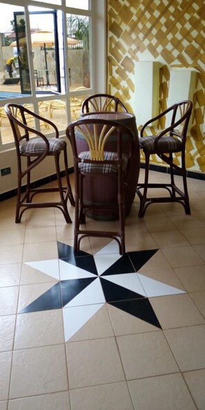 Un coin repas avec un sol orné d’un motif en étoile, des chaises en bois et une table.