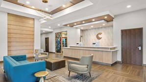 Una zona de recepción moderna con un panel de madera, mostrador de recepción, un sofá azul y un sillón gris.