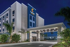 Un hotel Comfort Suites con diseño moderno, que cuenta con una entrada destacada con galería techada y vista despejada al estacionamiento.