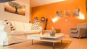 Een woonkamer met een witte bank, een salontafel en een fauteuil met een patroon.