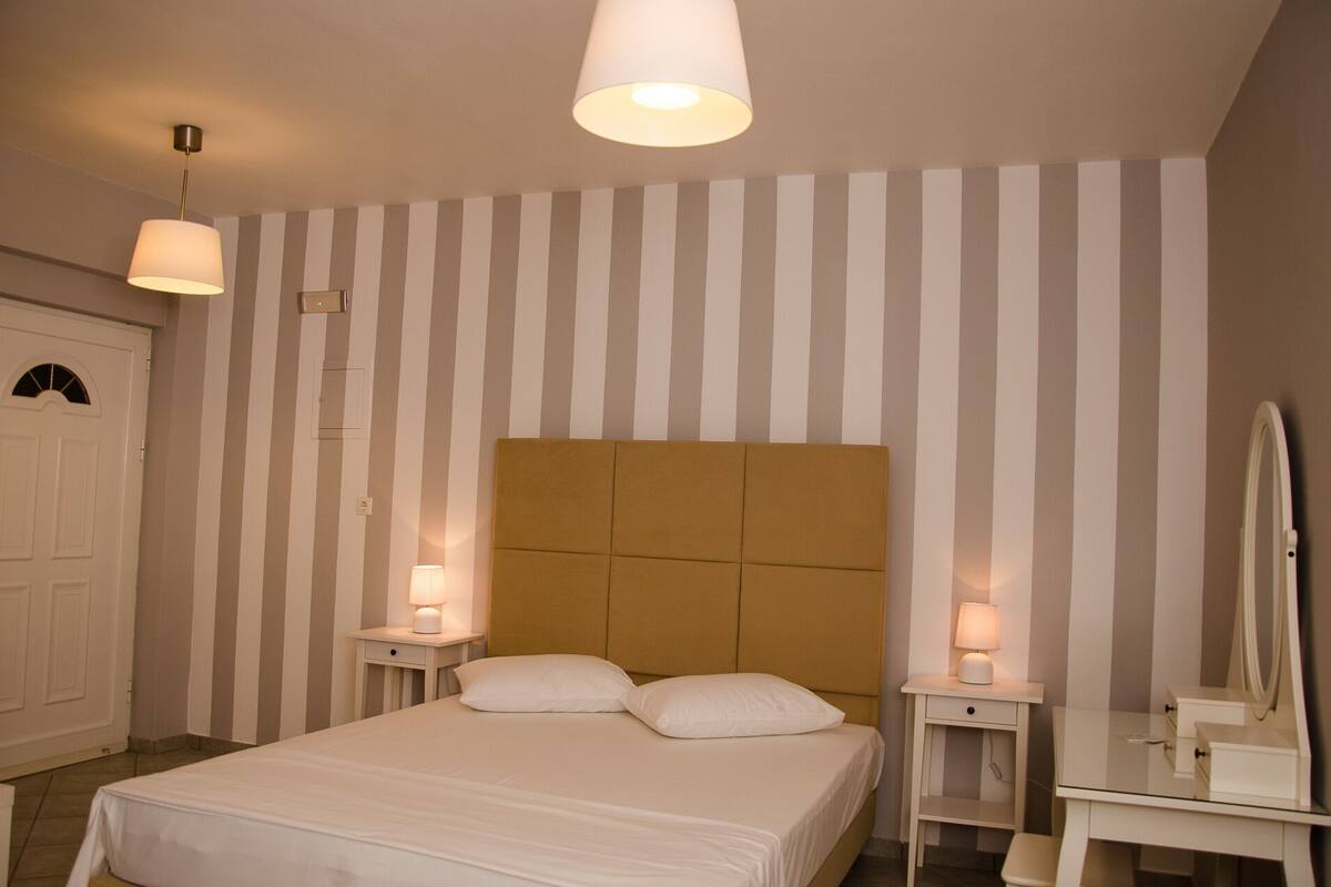 A hotel room with a bed, two bedside tables with lamps, a mirror, and a door.
