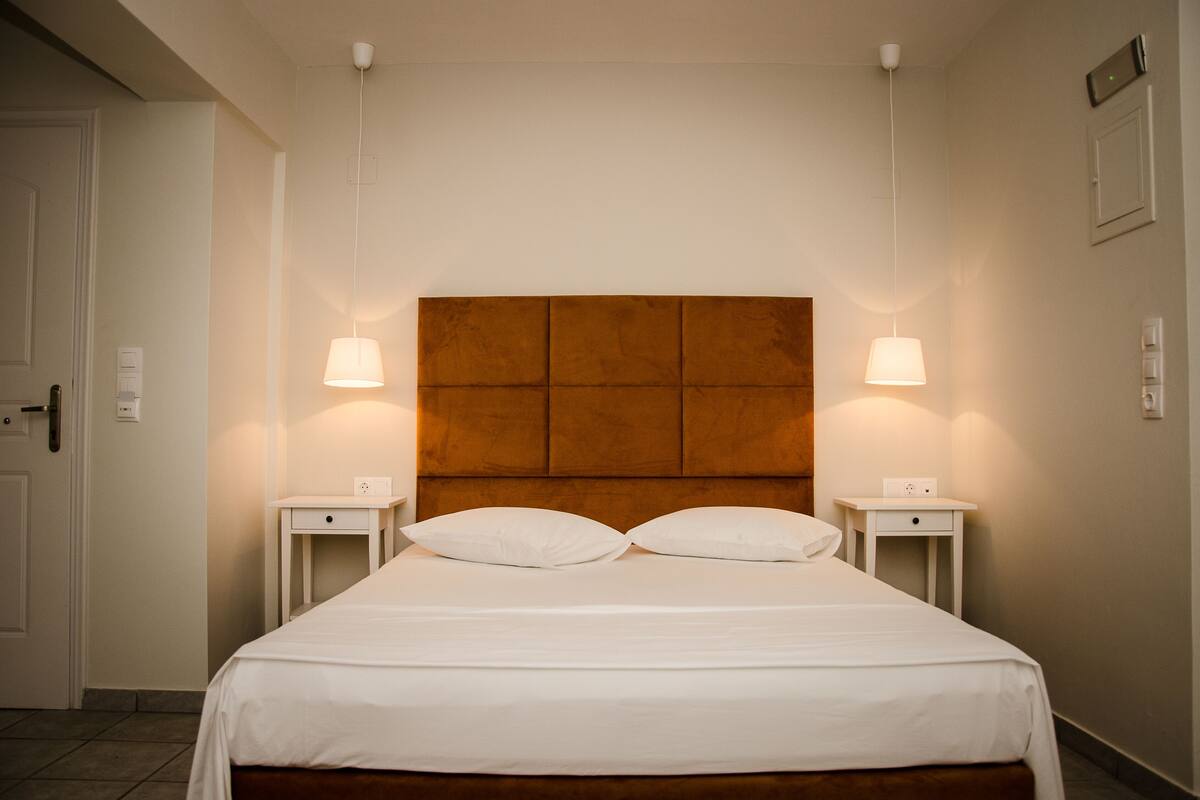 A hotel room with a large bed, two bedside tables, and a wooden headboard.