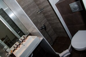 A modern bathroom with a white sink, a handheld showerhead, and a toilet. - Bello Horizonte Rooms & Apartments (East Mani)