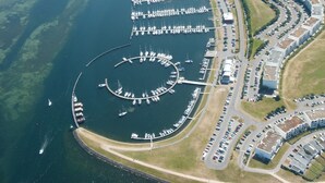 Vue aérienne d’une marina où sont amarrés de nombreux bateaux, avec des quais reliés entre eux et des zones de stationnement adjacentes.