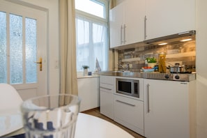 A compact kitchen with white cabinets, a stainless steel range, and a window with frosted glass.